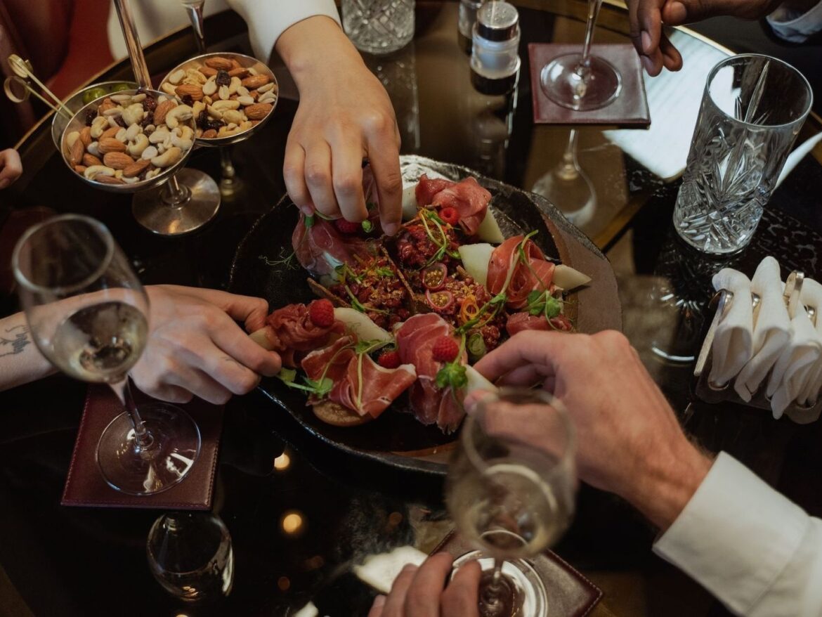 Gourmetanretning og vinglas på et bord, mens gæster deler maden