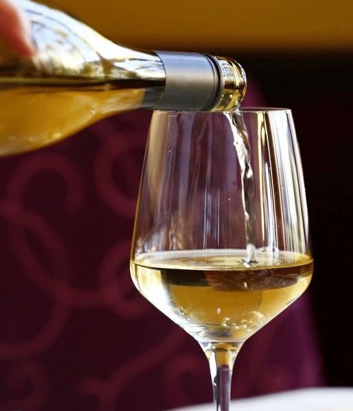Hvidvin hældes i et vinglas som eksempel på vin til mad